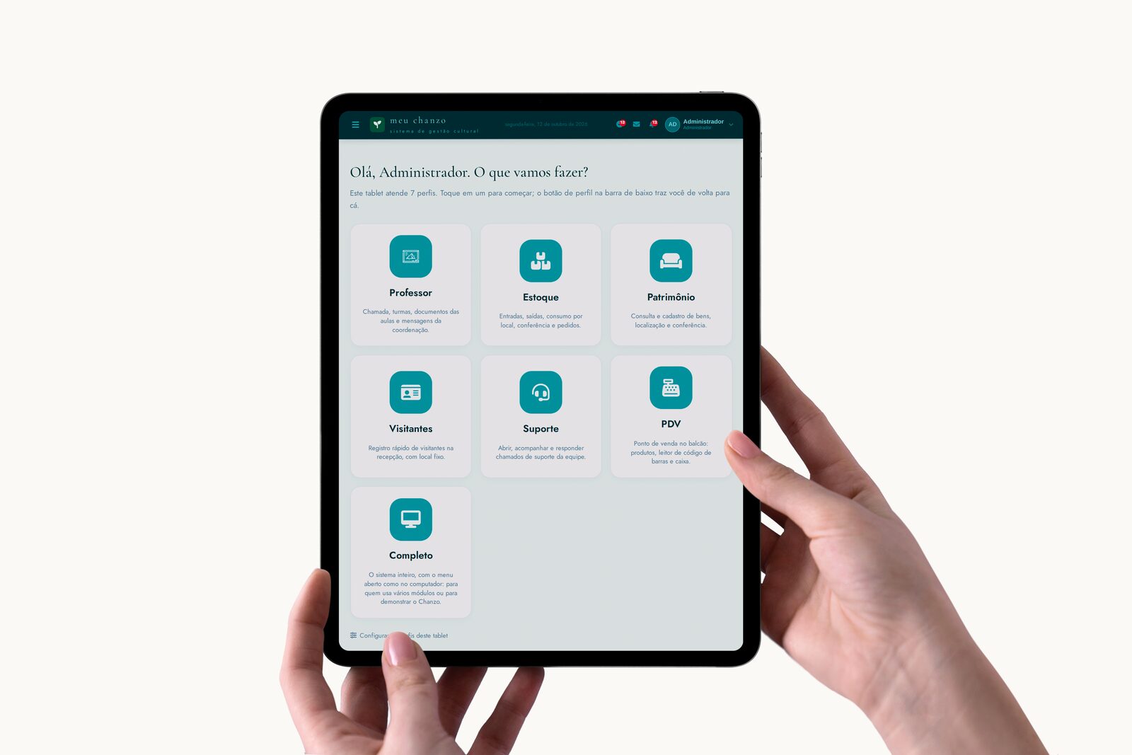 Tablet nas mãos mostrando o Início do Chanzo, com um botão para cada perfil: Professor, Estoque, Patrimônio, Visitantes, Suporte, PDV e Completo